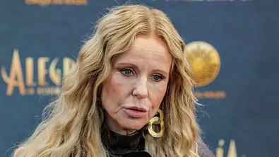 Katja Burkard steht mit offenen Haaren und ernster Miene vor einer Fotowand. - Foto: IMAGO / Oliver Langel