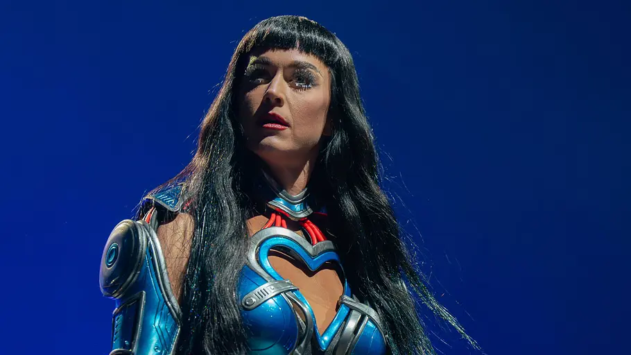 Katy Perry Katy Perry hat ein blaues metallartig aussehendes Bühnenkostüm an. Die schwarzen Haare fallen ihr über die Schulter und sie ist stark geschminkt.