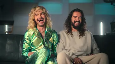 Bill und Tom Kaulitz sitzen auf einem Sofa. Bill trägt ein schillernd-grünes Fit. - Foto: Netflix Bill und Tom Kaulitz sitzen auf einem Sofa. Bill trägt ein schillernd-grünes Fit. - Foto: Netflix