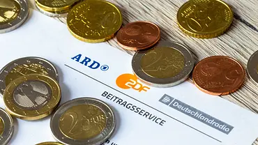 Einige Gold- und Bronzemünzen liegen auf einer GEZ-Rechnung - Foto:  IMAGO / Herrmann Agenturfotografie
