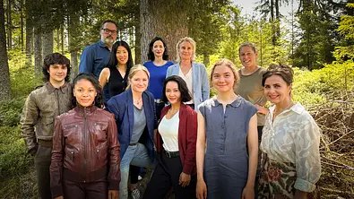 Regisseur Andreas Herzog mit den Darsteller:innen Carlo Grammling, Gloria Odosi, Julia Jentsch, Mai Duong Kieu, Hannah Schiller und Naomi Krauss sowie Produzentin Jean-Young Kwak, Autorin und Creative Producerin Kristin Derfler, der Produzentin Claudia Thieme und Kamerafrau Claire Jahn. - Foto: © SWR/Amalia Film/Fiete Haas
