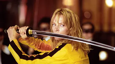 Uma Thurman steht in einem gelben Trainingsanzug und mit einem Katana bewaffnet vor etlichen Schlägern von O-Ren Ishii.  - Foto:  IMAGO / United Archives