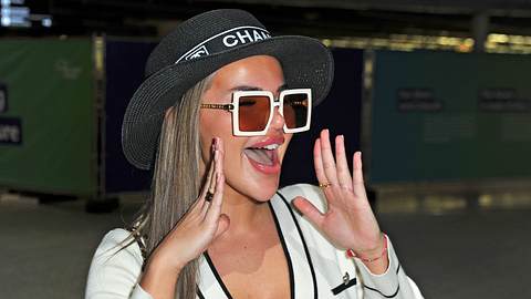 Kim Virginia am Flughafen mit Sonnenbrille und Hut. Sie reißt den Mund zu einem Schrei auf. - Foto:  IMAGO / STAR-MEDIA