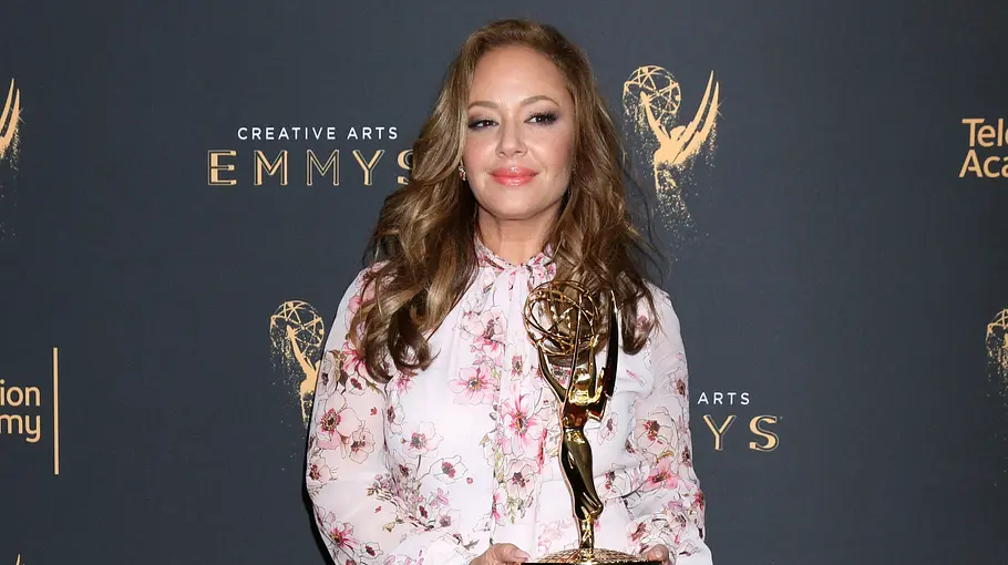 Leah Remini steht vor einer Fotowand und hält einen Emmy.