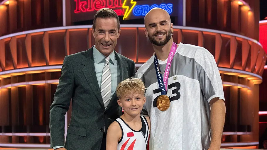Julian Weber bei „Klein gegen Groß“ Kai Pflaume steht bei „Klein gegen Groß“ mit dem jungen Herausforderer Maximilian und Speerwerfer Julian Weber vor dem Showlogo.