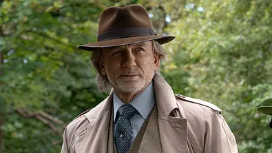 Daniel Craig als Benoit Blanc: Mann trägt Trechcoat, Anzug, Krawatte und Hut. - Foto: John Wilson/Netflix