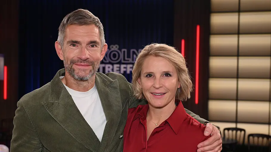 Susan Link und Micky Beisenherz Micky Beisenherz im grünen Sakko legt den Arm um Susan Link in roter Bluse. Beide lächeln in die Kamera.