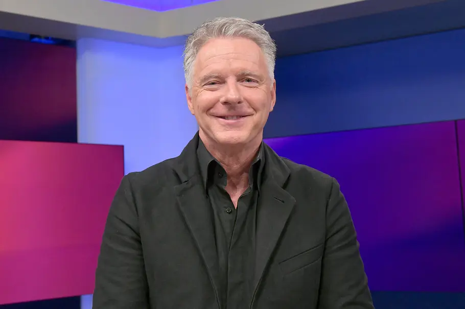 Jörg Pilawa Jörg Pilawa steht lächelnd vor einem bunten Hintergrund