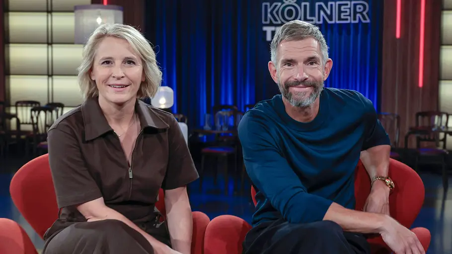 Susan Link und Micky Beisenherz Susan Link und Micky Beisenherz sitzen lächelnd in zwei roten Sesseln nebeneinander.