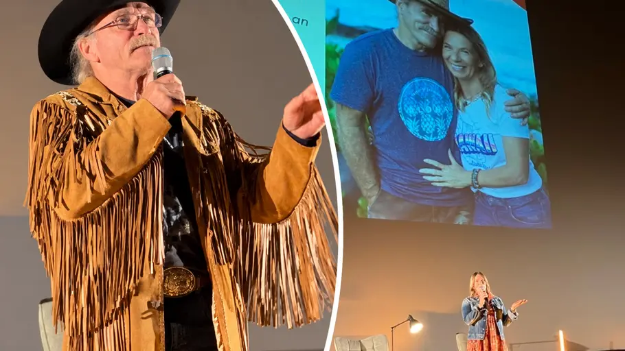 Reimann-Sabbeltour-Termine 2027 Die Reimanns im Oktober 2023 auf ihrer Sabbeltour: Konny Reimann trägt Cowboyhut und Fransenjacke. Manu steht mit Mikrofon auf einer Bühne vor einem projizierten Foto des Paares.