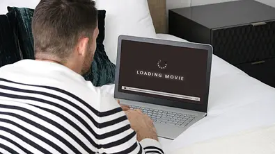 Ein Mann sitzt vor seinem Laptop. Auf dem Bildschirm ein Ladebildschirm - Foto: istock/glegorly