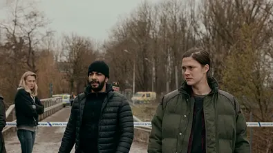 Eine männliche und eine weibliche Hauptfigur stehen in Winterkleidung bei Land der Sünde im Fokus - Foto: Netflix