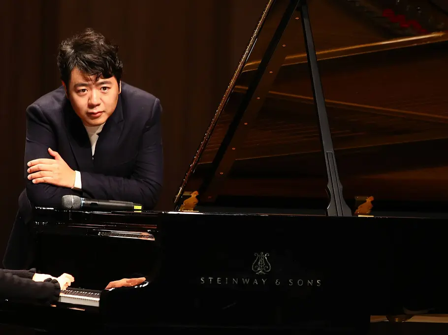 Starpianist Lang Lang lehnt sich über einen Flügel neben einem Mikrofon.