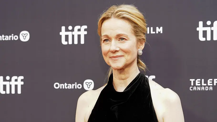 Laura Linney trägt ein schwarzes Neckholderkleid und Ohrringe vor einer dunklen Wand mit TIFF- und Sponsorenlogos.