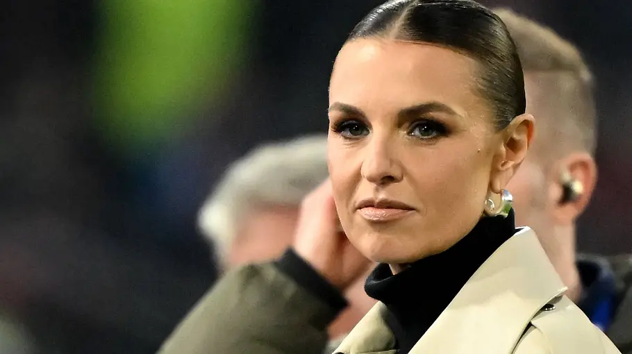 Laura Wontorra schwanger RTL Jobs Laura Wontorra mit zurückgekämmten Haaren trägt einen beigen Mantel und schwarzen Rollkragen. Hinter ihr stehen unscharf Personen.