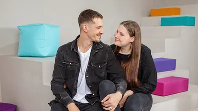 Tim Katzenbauer und Lavinia Wollny sitzen für ein Fotoshooting auf einer Treppe. Hinter ihnen sind bunte Elemente. - Foto: RTL2