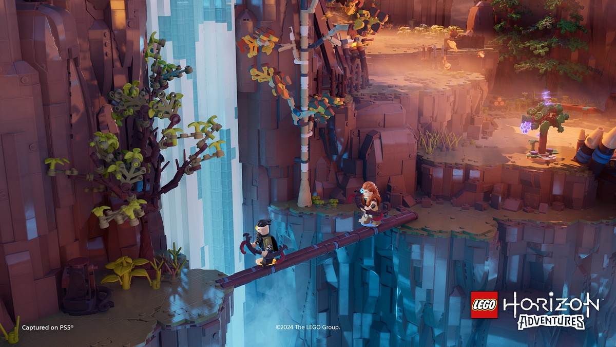 Aloy und Rost laufen in LEGO Horizon Adventures über einen Baumstamm vor einem Wasserfall.