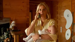 Lena Lorenz – Wahlverwandtschaft: Lena Lorenz (Judith Hoersch) hält ein Baby im Arm und telefoniert mit besorgtem Gesichtsausdruck mit einem Handy. Sie befindet sich in einer Küche, deren Wände mit Holz vertäfelt sind. - Foto: ZDF und Erika Hauri Lena Lorenz – Wahlverwandtschaft: Lena Lorenz (Judith Hoersch) hält ein Baby im Arm und telefoniert mit besorgtem Gesichtsausdruck mit einem Handy. Sie befindet sich in einer Küche, deren Wände mit Holz vertäfelt sind. - Foto: ZDF und Erika Hauri