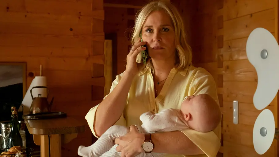 Lena Lorenz (Judith Hoersch) ist entsetzt, als sie feststellt, dass niemand sich um das schreiende Baby kümmert. Lena Lorenz – Wahlverwandtschaft: Lena Lorenz (Judith Hoersch) hält ein Baby im Arm und telefoniert mit besorgtem Gesichtsausdruck mit einem Handy. Sie befindet sich in einer Küche, deren Wände mit Holz vertäfelt sind.