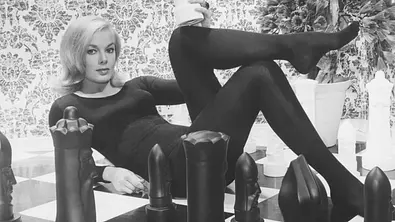 Leslie Parrish ganz in schwarz zwischen Schachfiguren. - Foto: IMAGO / Everett Collection Leslie Parrish ganz in schwarz zwischen Schachfiguren. - Foto: IMAGO / Everett Collection