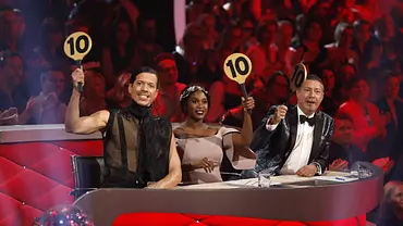 Drei Jury-Mitglieder sitzen an einem rot beleuchteten Jury-Pult in einer TV-Tanzshow und halten jeweils eine Bewertungstafel mit der Zahl 10 hoch, während im Hintergrund ein jubelndes Publikum zu sehen ist. - Foto: imago images / Future Image Drei Jury-Mitglieder sitzen an einem rot beleuchteten Jury-Pult in einer TV-Tanzshow und halten jeweils eine Bewertungstafel mit der Zahl 10 hoch, während im Hintergrund ein jubelndes Publikum zu sehen ist. - Foto: imago images / Future Image