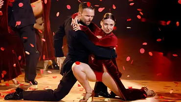 Ein Tanzpaar in eleganter Abendgarderobe performt eine leidenschaftliche Szene auf der „Let’s Dance“-Bühne, während rote Blütenblätter durch die Luft fallen. - Foto: IMAGO / Panama Pictures