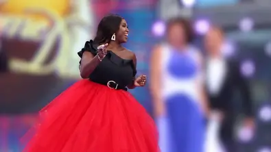 Motsi Mabuse im ausladenden roten Rock neben ihren Jury-Kollegen von „Strictly Come Daning“. Diese sind verschwommen dargestellt, genau wie der Hintergrund. - Foto: IMAGO / ZUMA Press Wire Motsi Mabuse im ausladenden roten Rock neben ihren Jury-Kollegen von „Strictly Come Daning“. Diese sind verschwommen dargestellt, genau wie der Hintergrund. - Foto: IMAGO / ZUMA Press Wire