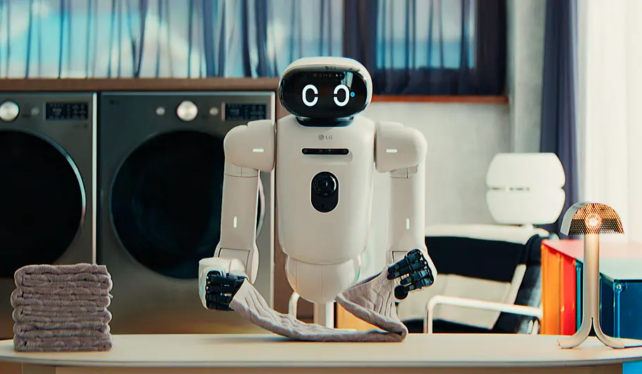 lg-cloid-ces-2026-tvmovie Der LG CLOiD legt die Wäsche zusammen vor zwei Waschmaschinen.