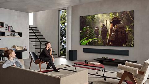 Zwei Personen sitzen in einem stylischen Wohnzimmer, der LG OLED TV G5 2025 hängt wie ein Gemälde an der Wand. - Foto: © 2009-2025 LG Electronics
