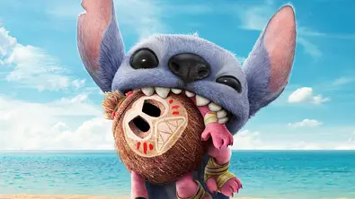 Man sieht das Alien Stitch, das wie ein blauer Chinchilla aussieht und an einem Strand sitzt. Stitch hat ein kleines Kokosnuss-Monster, bekannt als Kakamora, aus dem Film „Vaina“ im Mund. - Foto: themoviedb.org Man sieht das Alien Stitch, das wie ein blauer Chinchilla aussieht und an einem Strand sitzt. Stitch hat ein kleines Kokosnuss-Monster, bekannt als Kakamora, aus dem Film „Vaina“ im Mund. - Foto: themoviedb.org