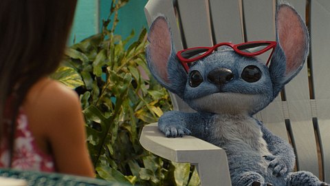 Stitch sitzt auf einem Stuhl und hat seine Sonnenbrille auf die Stirn geschoben. - Foto: Walt Disney Studios