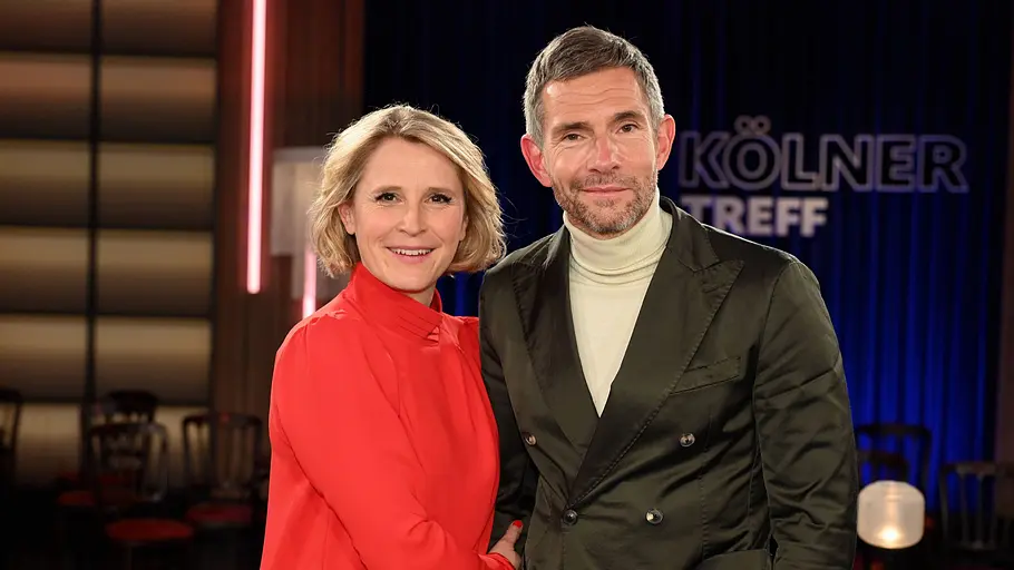 Susan Link und Micky Beisenherz moderieren den „Kölner Treff“ Susan Link und Micky Beisenherz stehen lächelnd im Studio des „Kölner Treff“.