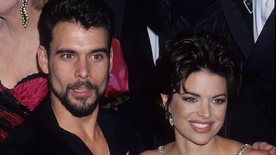 Lisa Rinna im schwarzen Kleid mit glitzernden Trägern steht neben Robert Kelker-Kelly im schwarzen Anzug mit roter Schleife.
