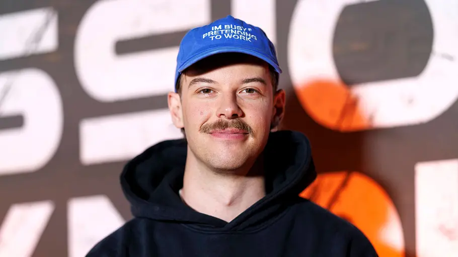 Aditotoro steht mit Kappe auf dem Red Carpet und lächelt zufrieden in die Kamera.