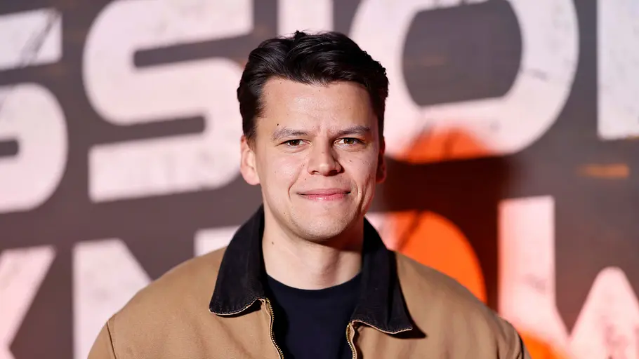 Paul Luca Fischer steht auf dem Red Carpet und lächelt etwas verunsichert in die Kamera.