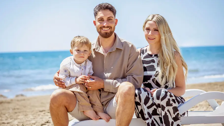 Loredana Wolly und Servet sitzen mit Sohn Aurelio am Strand.