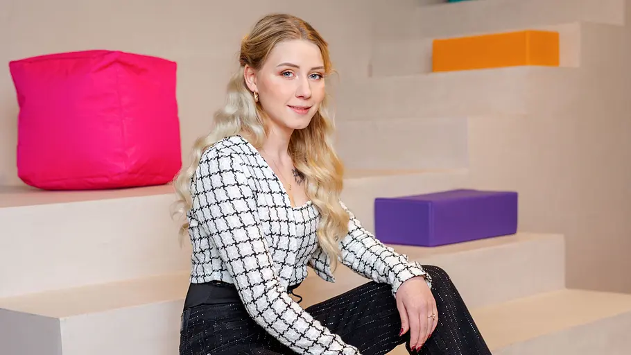 Loredana Wollny sitzt für ein Fotoshooting auf einer Treppe. Sie ist von bunten Elementen umgeben.