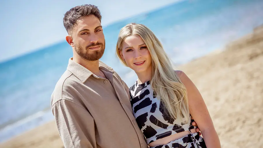 Loredana Wollny und Servet Loredana Wollny und Servet stehen Arm in Arm am Strand und lächeln in die Kamera.
