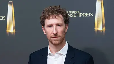 Louis Klamroth in dunklem Anzug und weißem Hemd vor einer Fotowand beim Deutschen Fernsehpreis - Foto:  IMAGO / Sven Simon