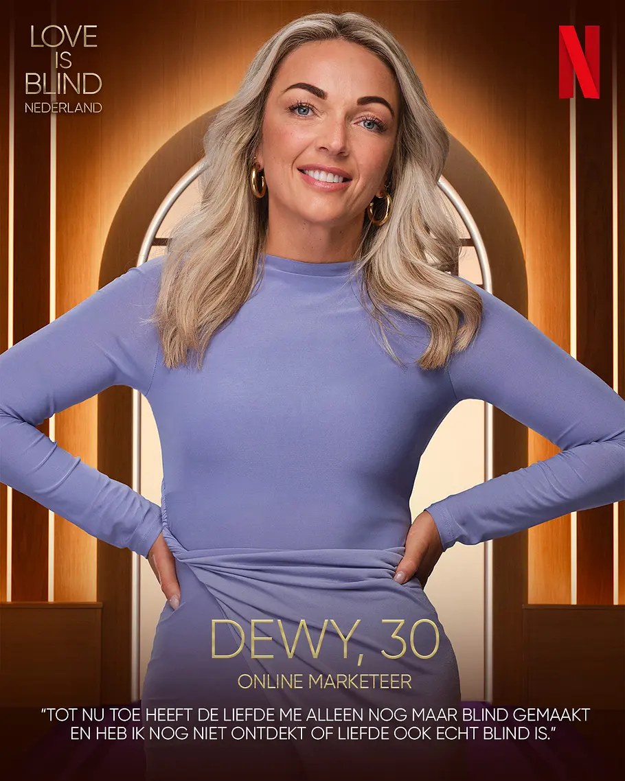 Love is Blind: Netherlands-Kandidat Dewy Alter, Beruf Dewy lächelt im fliederfarbenen Kleid mit den Händen an den Hüften. Auf dem Werbeplakat steht „Love is Blind Nederland“.