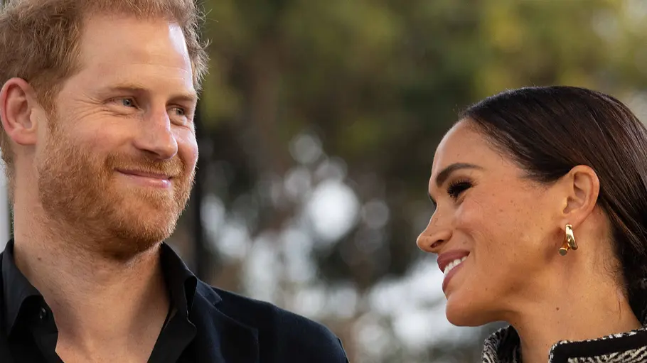 Prinz Harry und Herzogin Meghan lächeln sich bei einem öffentlichen Auftritt eng an und wirken vertraut.