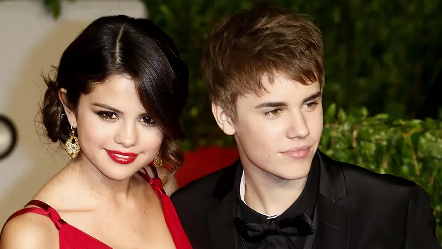 Selena Gomez und Justin Bieber posieren bei einem Event eng nebeneinander in eleganter Abendgarderobe und blicken in Richtung der Kameras.
