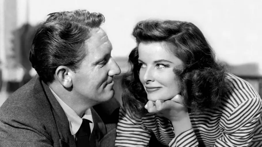 Spencer Tracy und Katharine Hepburn schauen sich auf einer Schwarz-Weiß-Aufnahme nah und vertraut in die Augen, während sie einen Baseball in der Hand hält.