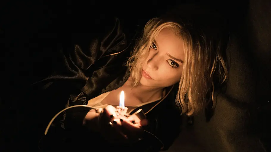 Anya Taylor-Joy in „Lucky“ liegt im Dunkeln und hält ein brennendes Feuerzeug.