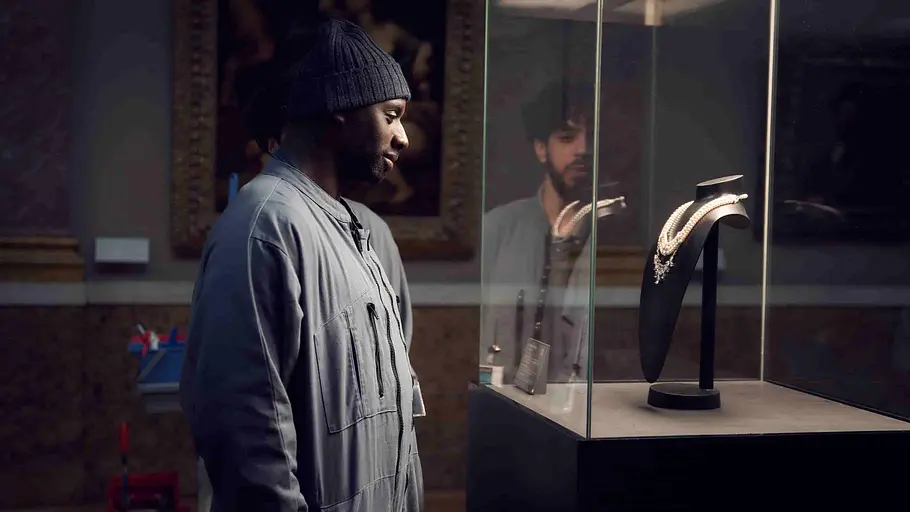 Der als Reinigungskraft verkleideter Dieb „Lupin“ schaut ausgestellte Juwelen im Louvre an.