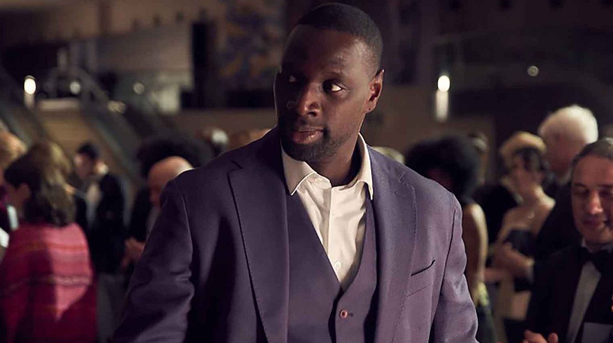 Assane Diop Lupin Lupin steht in einer Menschenmenge und schaut sich um