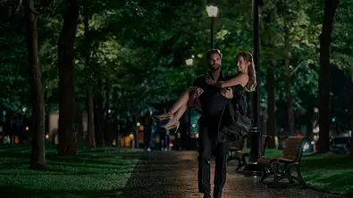 Adam läuft durch einen Park, er hält Olive im Brautstil. - Foto: Prime Video