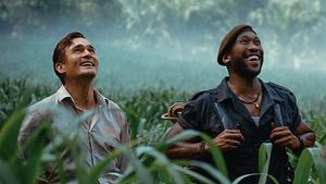 Mahershala Ali und Rupert Friend stehen in „Jurassic World: Die Wiedergeburt“ als Duncan Kincaid und Martin Krebs im Gras und schauen fasziniert nach oben.  - Foto: © Universal Studios