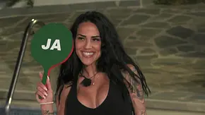 Elena Miras hält lächelnd ein grünes „Ja“-Schild in die Kamera, während sie am Pool der „Make Love, Fake Love“-Villa steht. - Foto: RTL Elena Miras hält lächelnd ein grünes „Ja“-Schild in die Kamera, während sie am Pool der „Make Love, Fake Love“-Villa steht. - Foto: RTL
