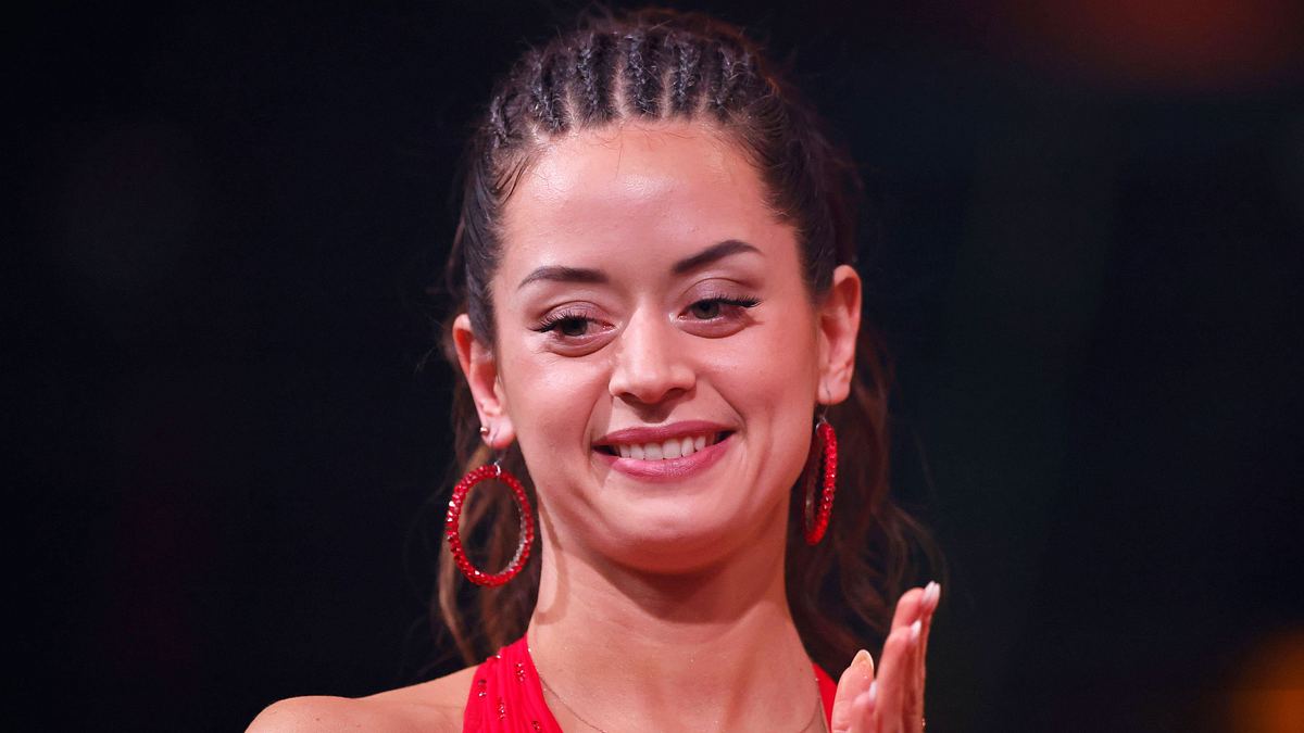 Kehrt Malika Dzumaev je zu „Let’s Dance“ zurück? Malika Dzumaev mit geflochtenen Haaren und in einem roten Kleid schaut besorgt zu Boden.